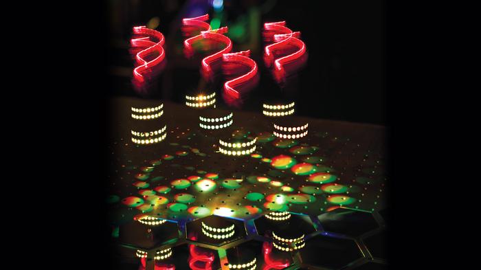 Artistic representation of hyper-Raman optical activity: twisted light (red helices) incident on molecules arranged on a helical scaffold (white dots) produce hyper-Raman scattering spectra (multicoloured light patches) that express ‘chirality’ (patches in spiral patterns and broken mirror). @ Ventsislav Valev and Kylian Valev