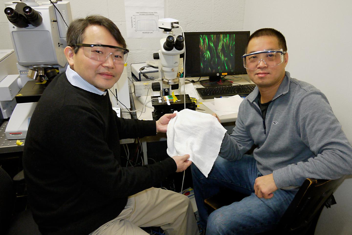 University of Maryland Chemistry and Biochemistry Professor YuHuang Wang (left) and Physics Professor Min Ouyang hold a swatch of their new fabric that can automatically adjust its insulating properties to warm or cool a human body. @ Faye Levine, University of Maryland