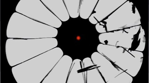 Electron microscope image of one of the photonic crystal fibres made at MPL for this research. The glass is black, the air is grey and the red dot illustrates the focus.