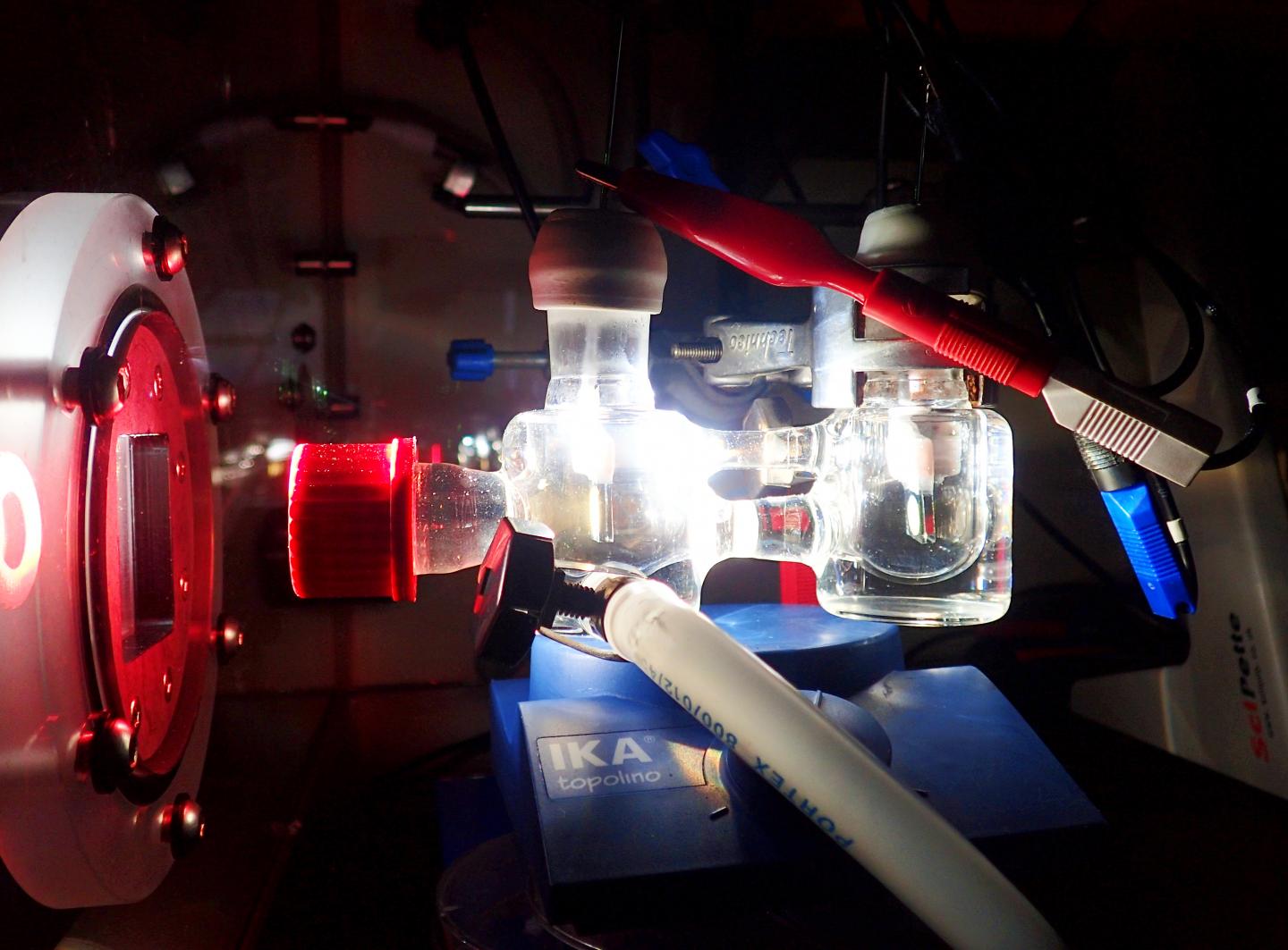 Experimental two-electrode setup showing the photoelectrochemical cell illuminated with simulated solar light. @ Katarzyna Sokó