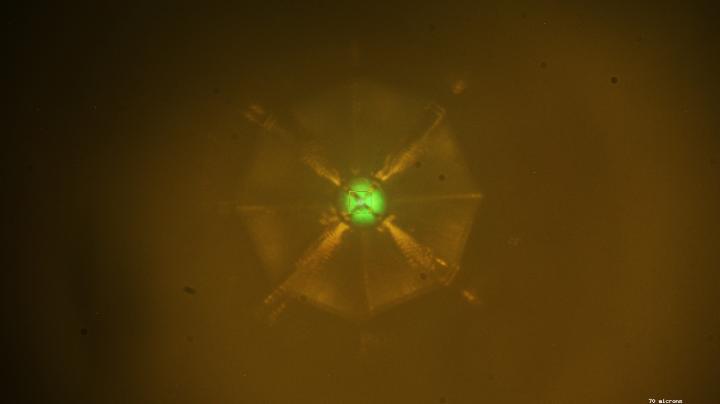Scientists bombarded a sample of a new superconducting material with X-rays to study its structure at the Advanced Photon Source at Argonne National Laboratory. The X-ray fluorescence creates the greenish color at the sample (center). @ Drozdov et al.